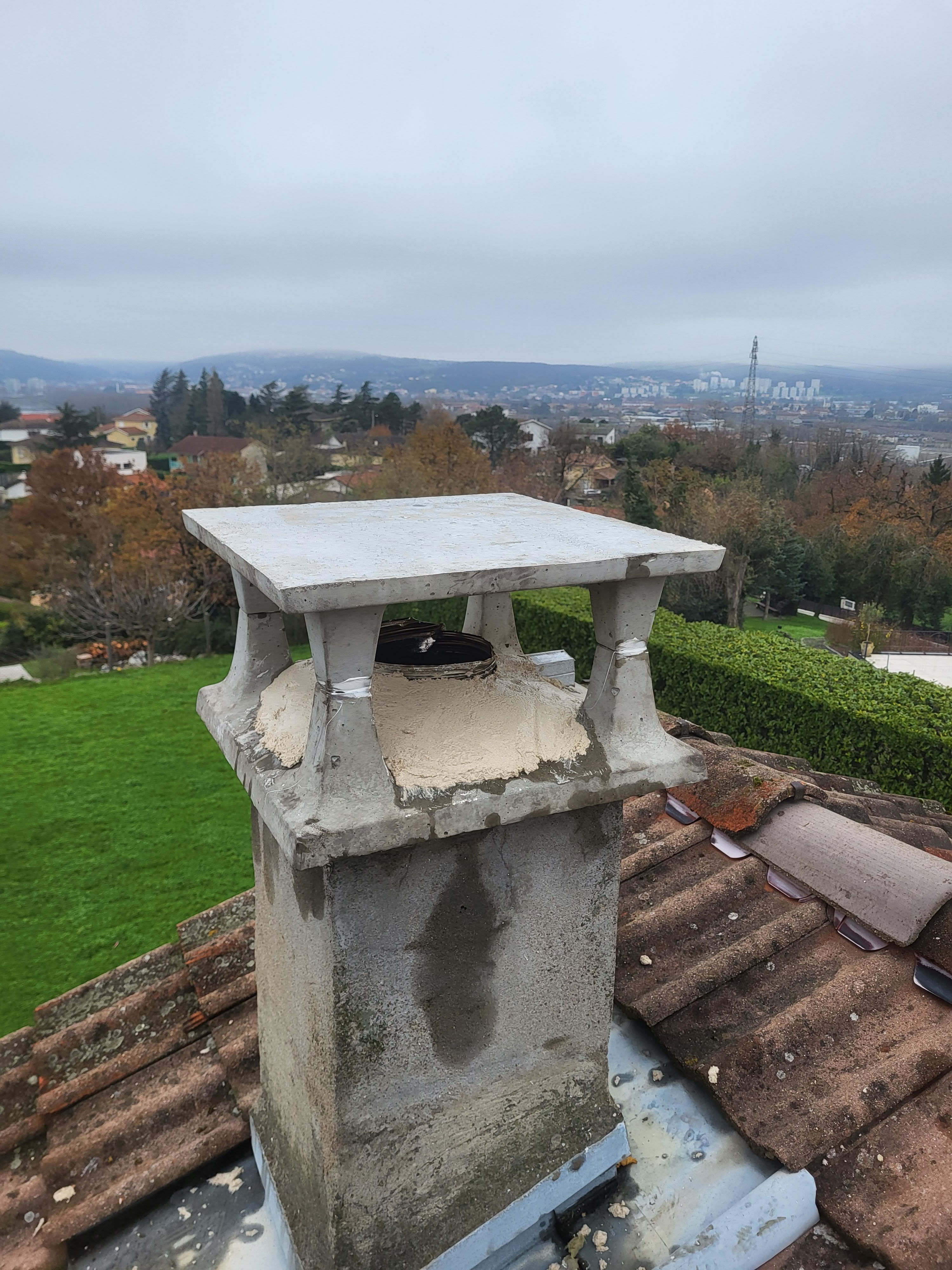 Cheminée à Vienne avec chapeau neuf posé par un ramoneur professionnel pour éviter les infiltrations d'eau. Vue panoramique sur la ville en arrière-plan depuis le toit